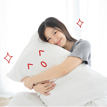 White long pillow with red smiley graphic, hugged in bed