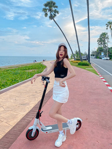 Black sleeveless crop top with text, white mini skirt, and light cap