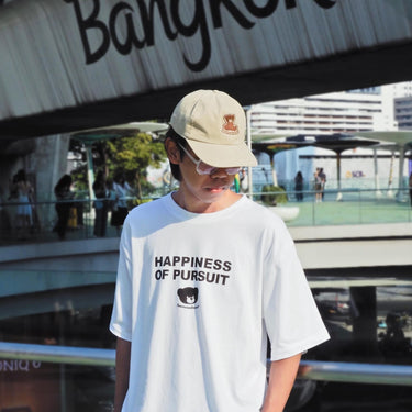 Model wearing a cool street t-shirt with the phrase Happiness of Pursuit, showcasing urban fashion style