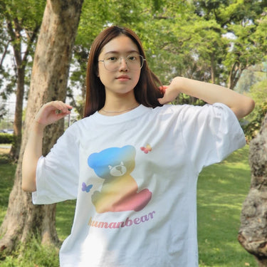 Model wearing Human Touch rainbow bear cool street t-shirt in a park with trees