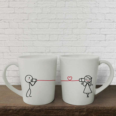 Cute couples coffee mugs featuring stick figures using cups with a heart string, ideal anniversary keepsakes for him and her