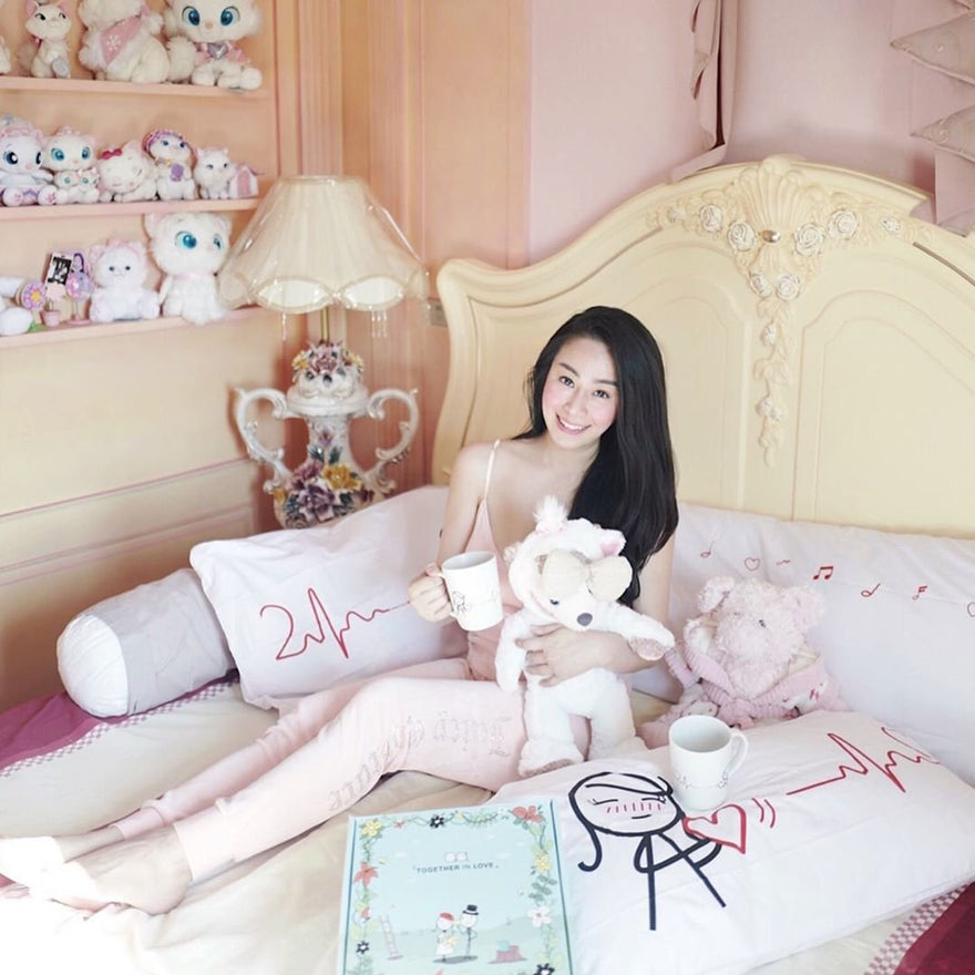 A person relaxing on a bed with customized gifts for loved ones, including personalized pillows and plush toys.