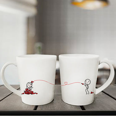 Couples coffee mugs featuring cute stick figures connected by a heart string, ideal anniversary gift mugs for couples.